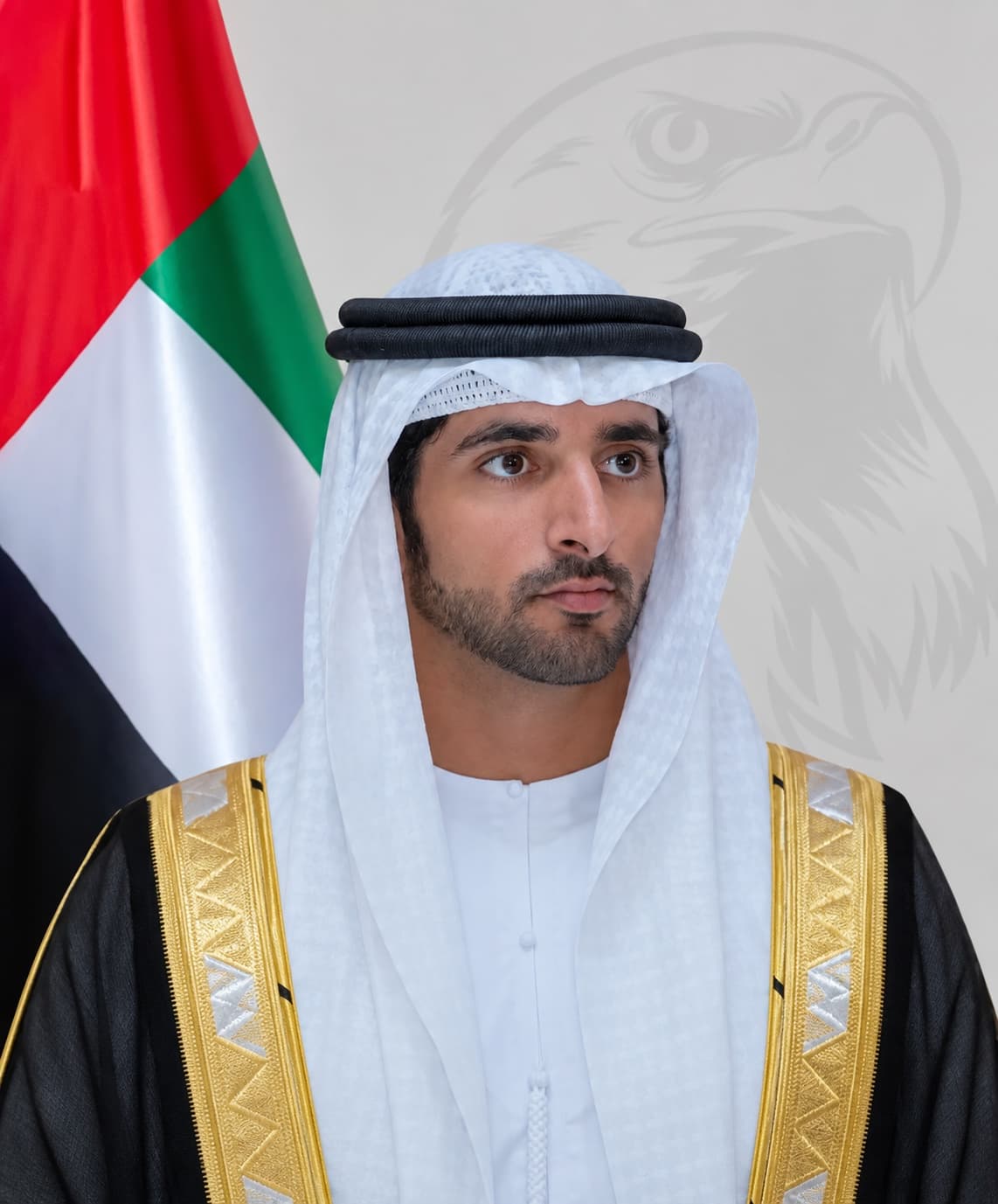 Official portrait of H.H. Sheikh Hamdan bin Mohammed bin Rashid Al Maktoum with the UAE flag and a falcon emblem